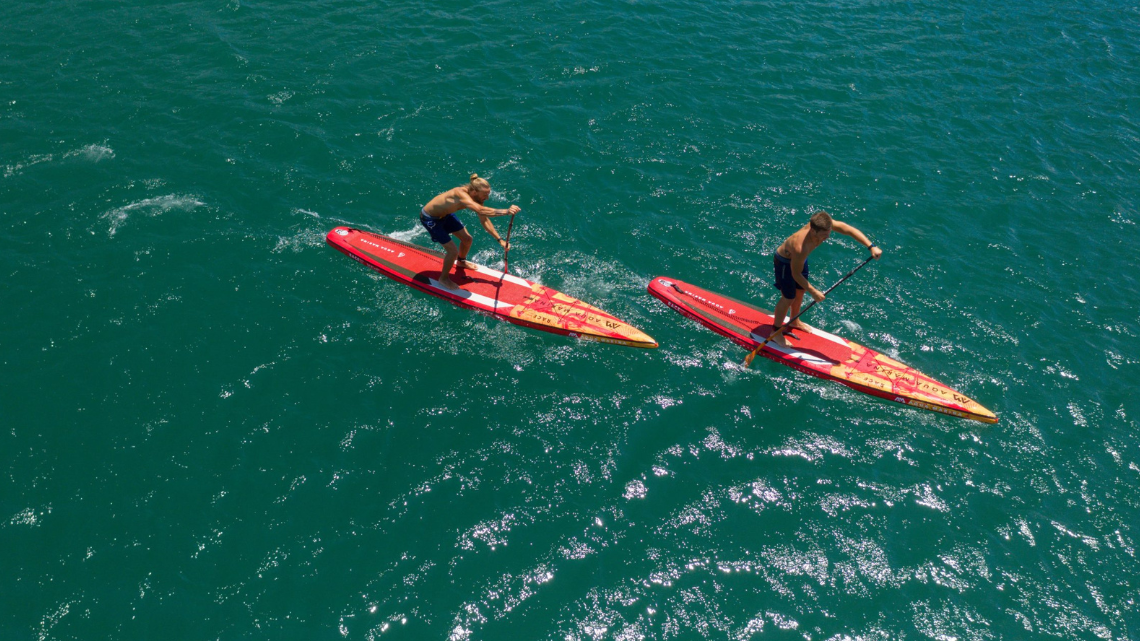 two people racing on long inflatable supboards